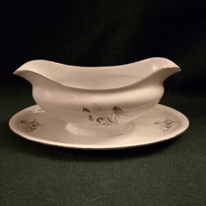 White and Gold Gravyboat with Attached Drip Tray, And Elegant Floral Design.